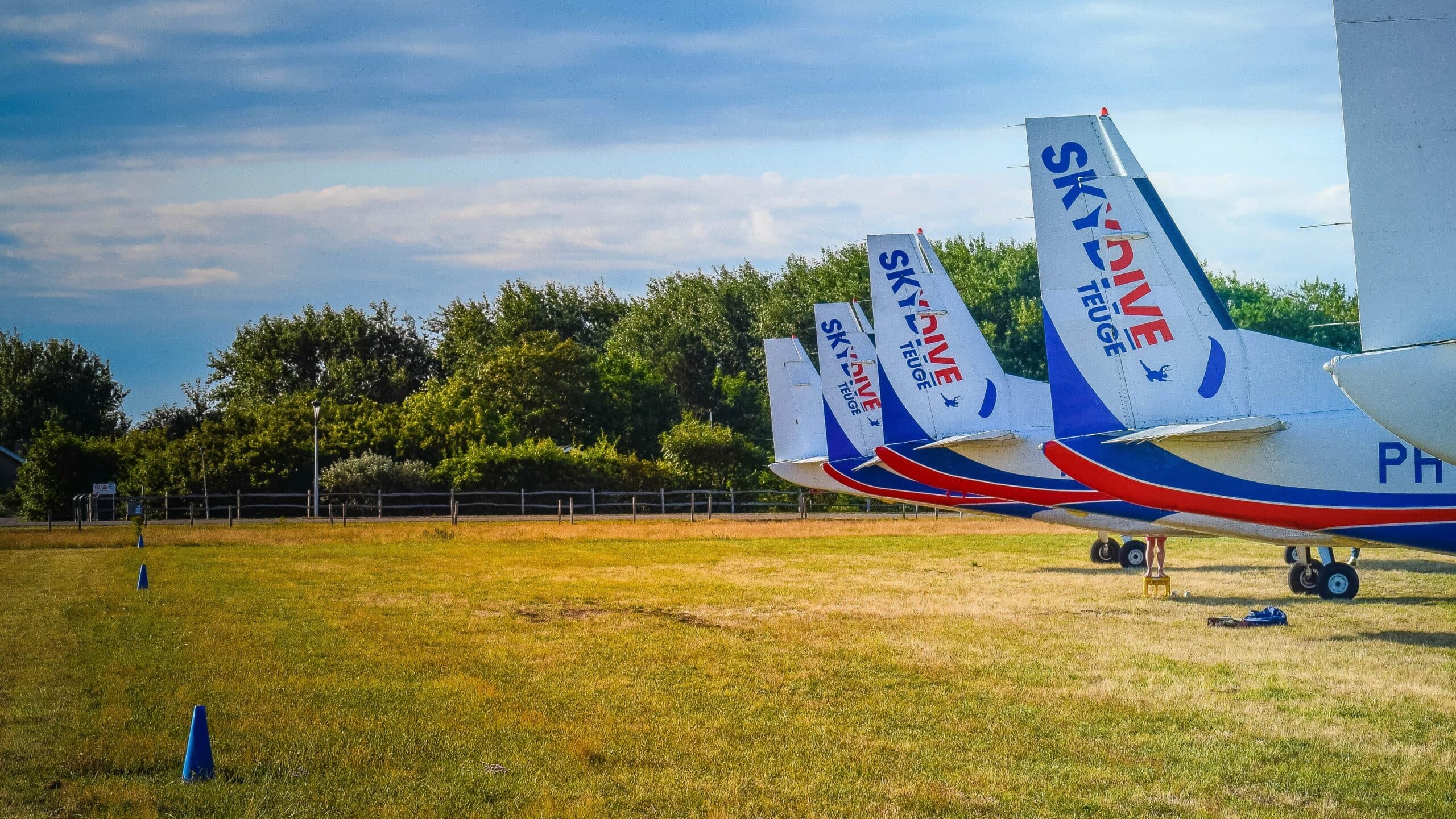 Staartvleugels van vliegtuigen met het Skydive Teuge-logo op het vliegveld